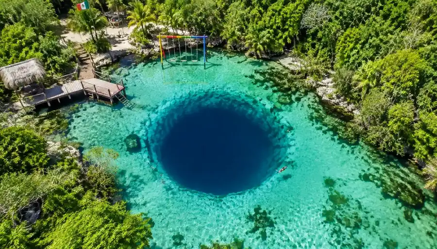 Aerial view of Kaan Luum Lagoon with its round deep-blue cenote and a wooden pier