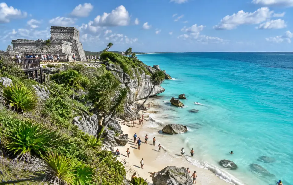 Tulum ruins on the cliff above a sandy cove with turquoise Caribbean water